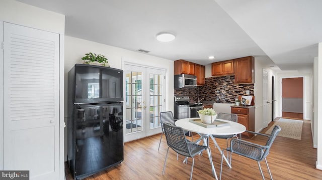 kitchen featuring appliances with stainless steel finishes, french doors, decorative backsplash, brown cabinets, and light wood-style floors