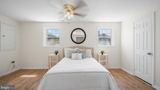bedroom with multiple windows, light wood-type flooring, and baseboards