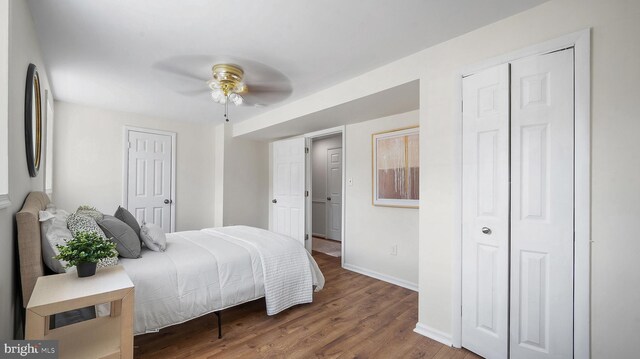 bedroom with baseboards, wood finished floors, ceiling fan, and a closet
