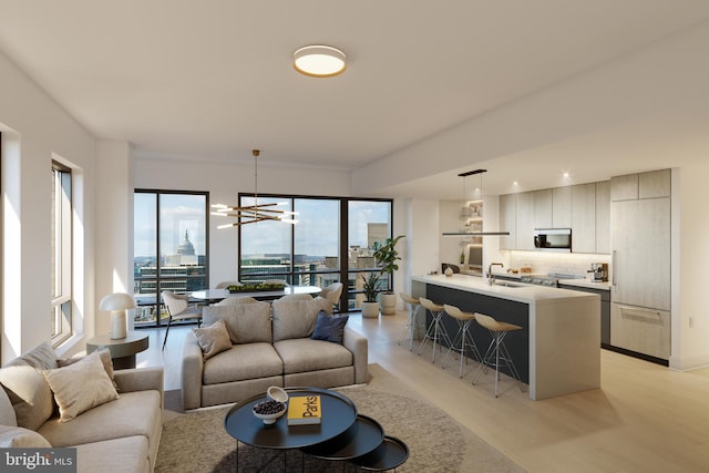 living room featuring light hardwood / wood-style flooring, a chandelier, sink, and a wealth of natural light