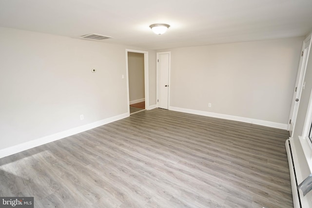 spare room with hardwood / wood-style flooring and a baseboard heating unit