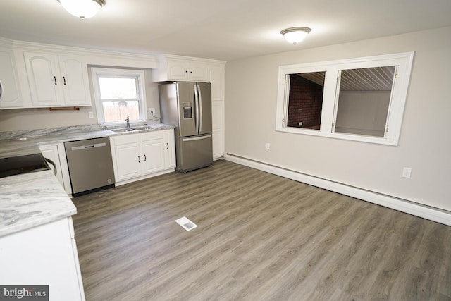 kitchen with baseboard heating, white cabinetry, stainless steel appliances, and wood-type flooring