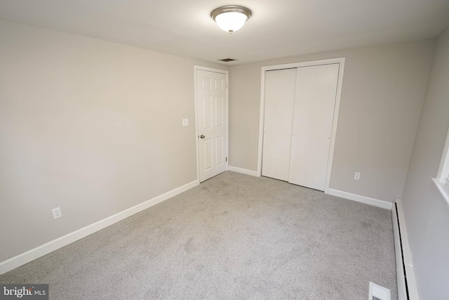 unfurnished bedroom featuring a closet, light carpet, and a baseboard radiator