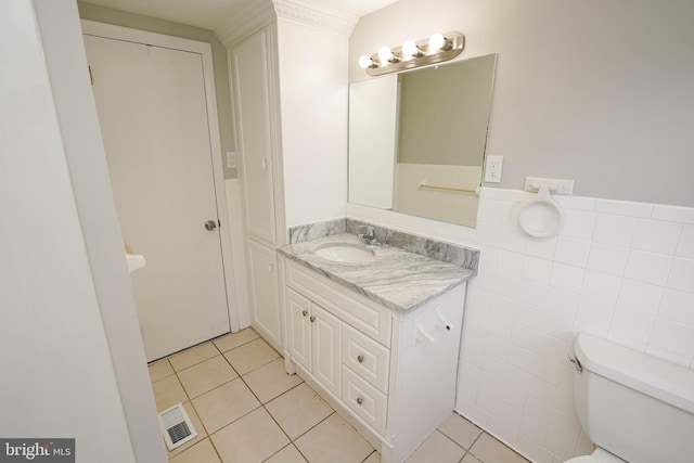 bathroom with vanity, toilet, tile patterned floors, and tile walls