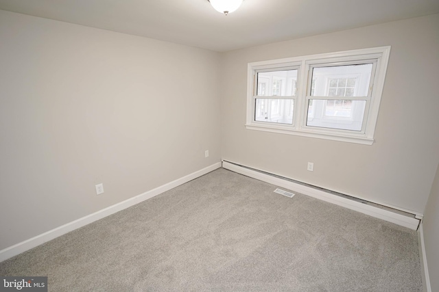 spare room featuring baseboard heating and light colored carpet