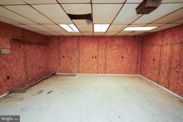 basement featuring wood walls and a paneled ceiling