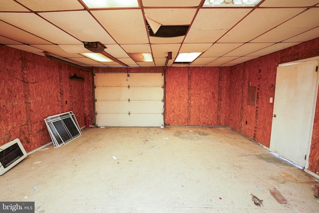 garage featuring a garage door opener, wooden walls, and heating unit