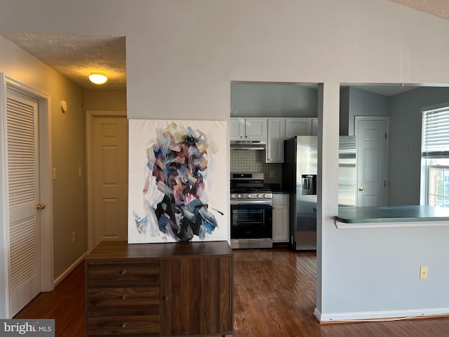 kitchen featuring stainless steel appliances, dark hardwood / wood-style flooring, white cabinetry, a textured ceiling, and tasteful backsplash