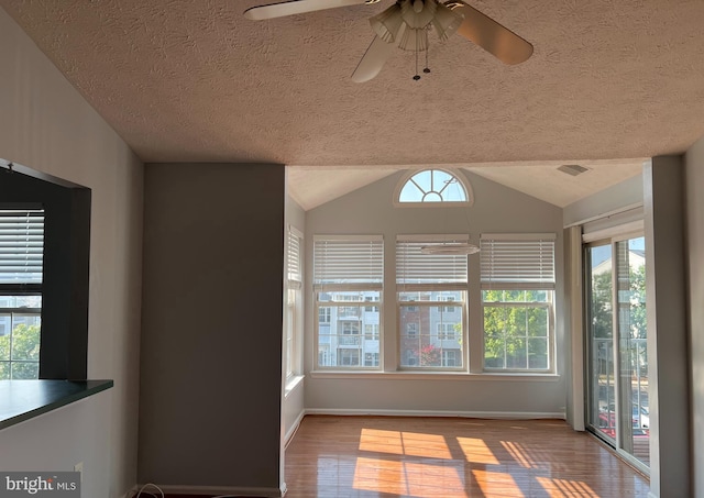 interior space featuring ceiling fan, hardwood / wood-style flooring, a textured ceiling, and vaulted ceiling