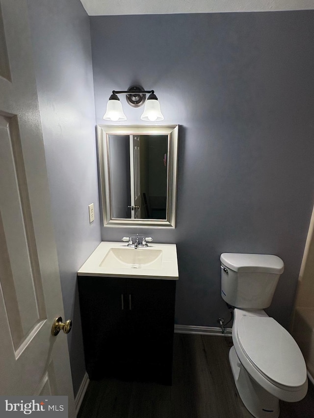 bathroom with toilet, vanity, and wood-type flooring