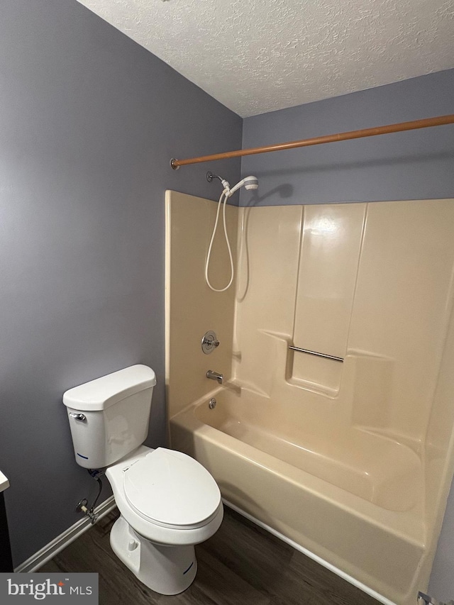 bathroom with a textured ceiling, shower / tub combination, hardwood / wood-style flooring, and toilet