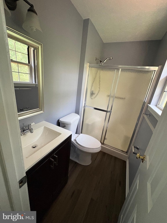 bathroom featuring a shower with door, toilet, vanity, and wood-type flooring