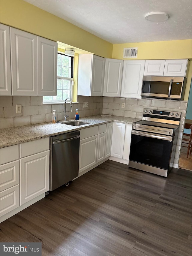 kitchen featuring sink, dark hardwood / wood-style flooring, stainless steel appliances, white cabinets, and decorative backsplash