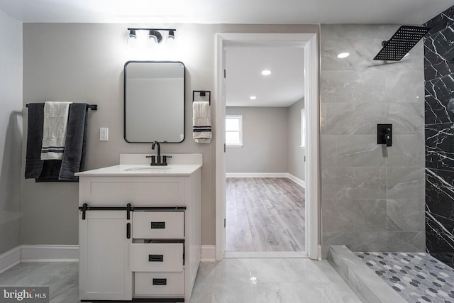 bathroom featuring hardwood / wood-style flooring, vanity, and tiled shower