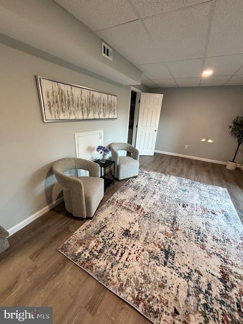 sitting room featuring dark hardwood / wood-style flooring and a drop ceiling