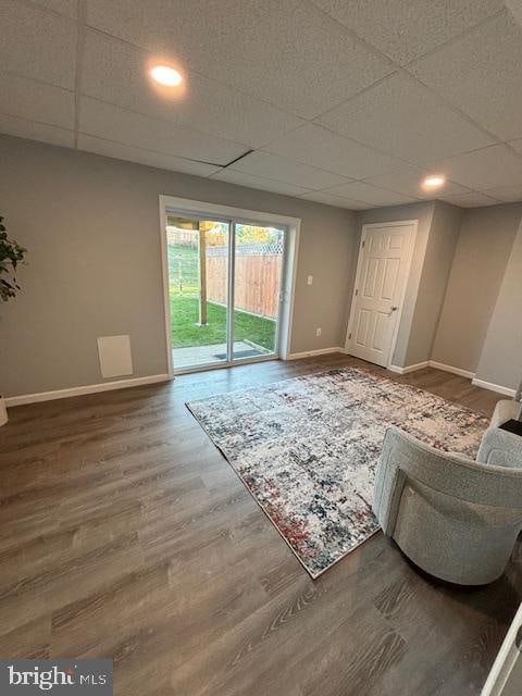 living room featuring wood-type flooring and a drop ceiling