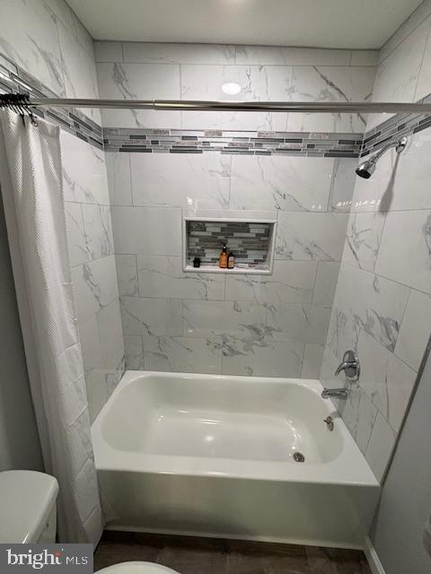 bathroom with shower / tub combo with curtain and toilet