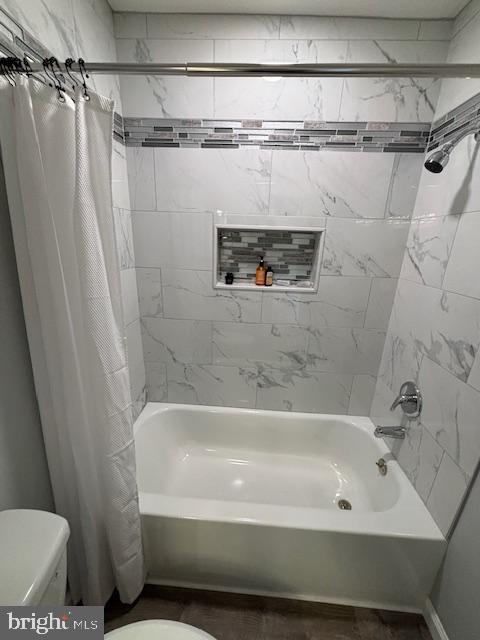 bathroom featuring shower / tub combo and toilet