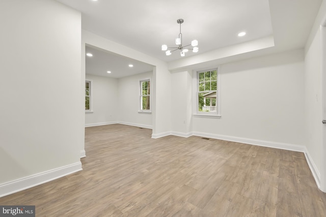 empty room with an inviting chandelier and light wood-type flooring