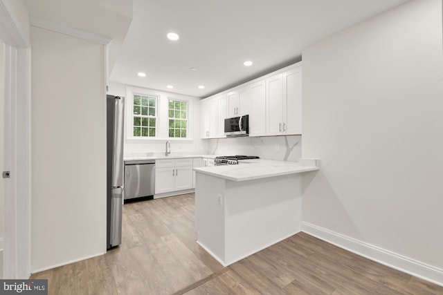 kitchen with decorative backsplash, light stone countertops, white cabinets, light wood-type flooring, and appliances with stainless steel finishes