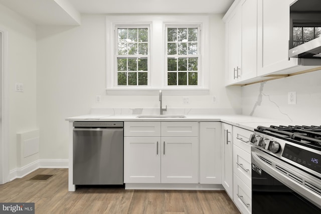 kitchen featuring appliances with stainless steel finishes, white cabinets, sink, and light hardwood / wood-style floors