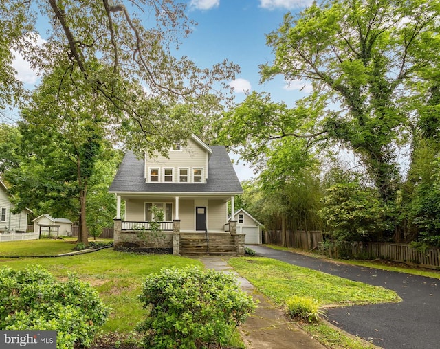 view of front facade featuring covered porch, an outdoor structure, a garage, and a front lawn