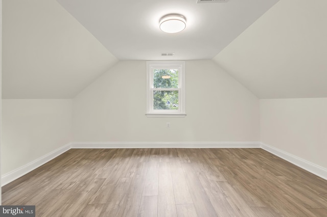 additional living space featuring vaulted ceiling and light wood-type flooring