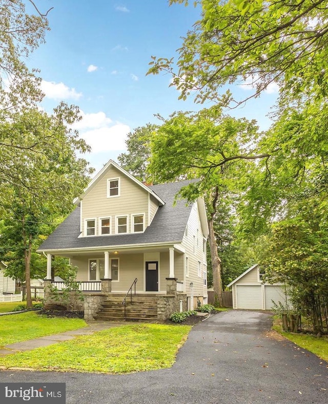 view of front of home with a front yard, an outbuilding, a garage, and covered porch