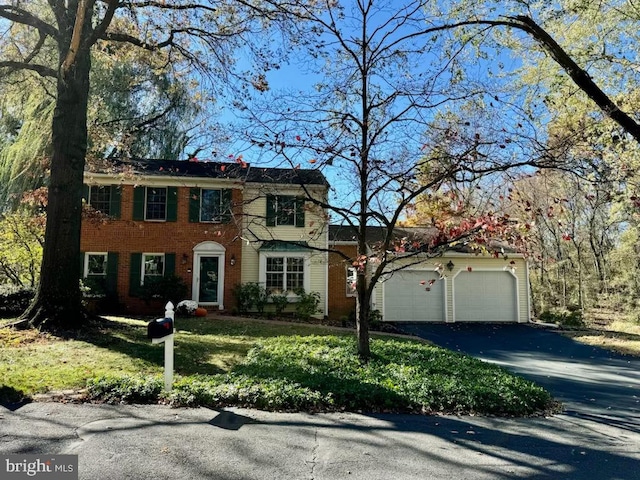 colonial inspired home with a garage and a front yard