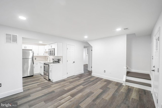 kitchen featuring tasteful backsplash, white cabinetry, appliances with stainless steel finishes, dark hardwood / wood-style floors, and sink