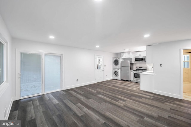 unfurnished living room featuring dark wood-type flooring and stacked washing maching and dryer