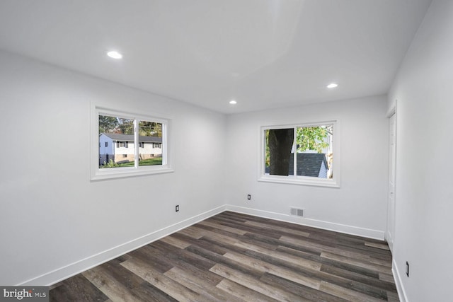 empty room with dark hardwood / wood-style floors and a healthy amount of sunlight