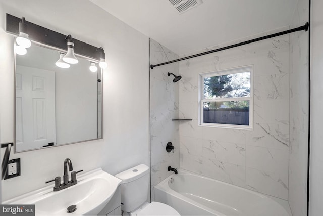 full bathroom featuring vanity, tiled shower / bath combo, and toilet