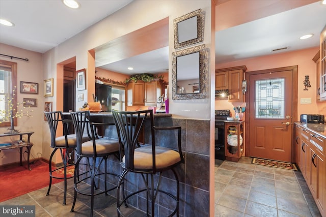 kitchen with black appliances, a kitchen bar, and plenty of natural light