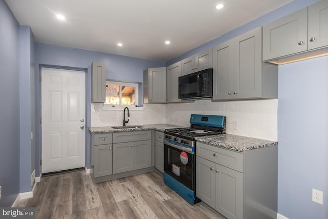 kitchen with gas range, gray cabinets, sink, and light wood-type flooring