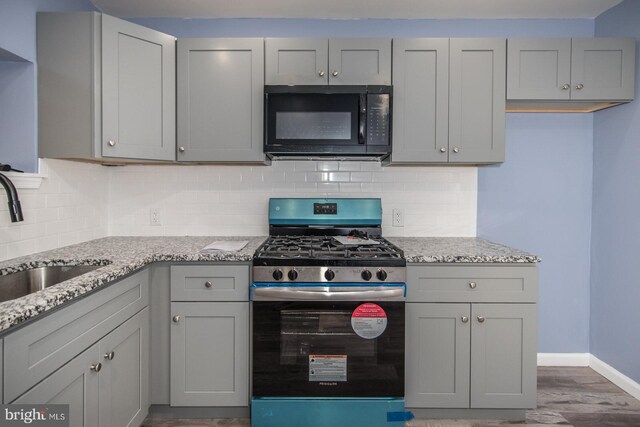 kitchen featuring gray cabinets, light stone countertops, sink, and stainless steel range with gas stovetop