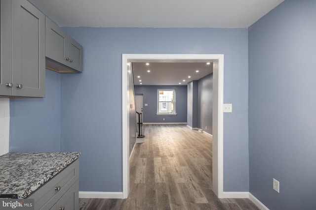 kitchen featuring stone countertops, dark wood-type flooring, and gray cabinetry