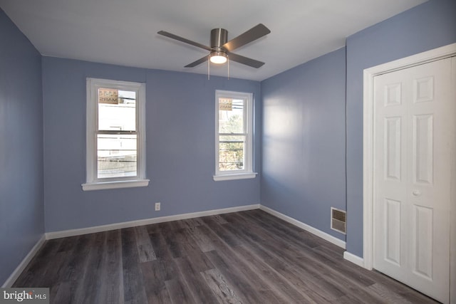 empty room with ceiling fan, dark hardwood / wood-style flooring, and plenty of natural light