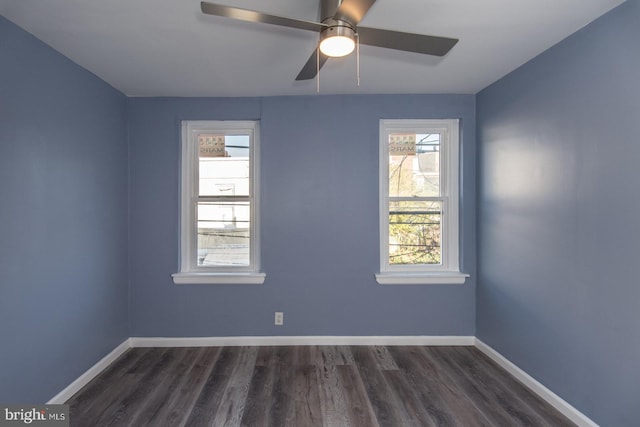 empty room featuring a wealth of natural light, ceiling fan, and dark hardwood / wood-style flooring