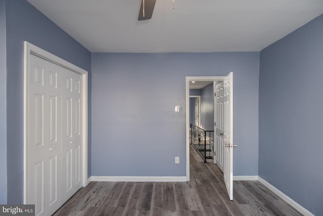 unfurnished bedroom featuring dark hardwood / wood-style flooring, a closet, and ceiling fan