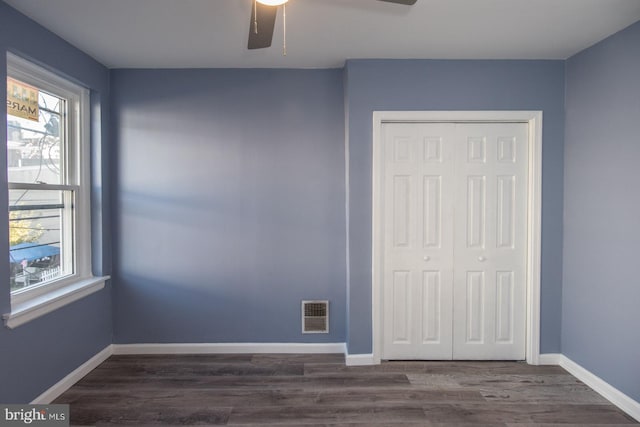 unfurnished bedroom with ceiling fan, a closet, and dark hardwood / wood-style flooring