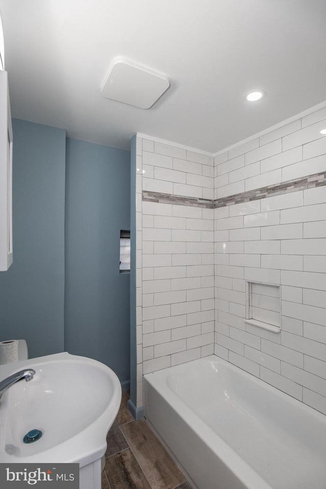 bathroom with hardwood / wood-style floors, sink, and tiled shower / bath combo