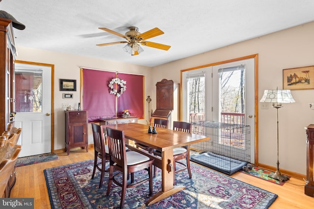 dining area featuring light wood-type flooring, a textured ceiling, and ceiling fan