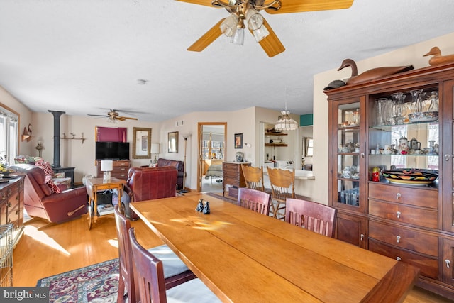 dining room featuring light wood-type flooring, a textured ceiling, and ceiling fan