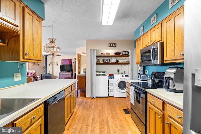 kitchen with light hardwood / wood-style floors, black appliances, a textured ceiling, pendant lighting, and independent washer and dryer