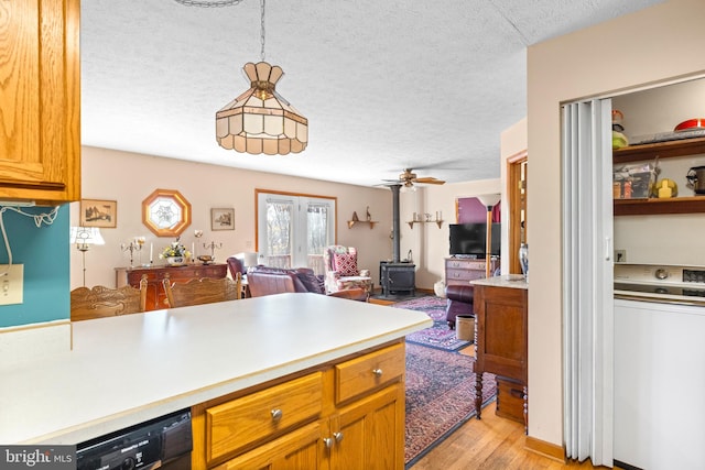 kitchen featuring dishwasher, ceiling fan, pendant lighting, light wood-type flooring, and washer / dryer