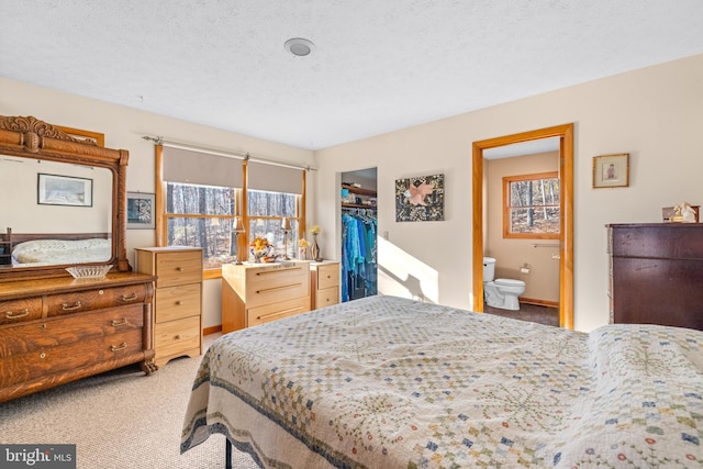 carpeted bedroom with ensuite bath, a textured ceiling, and a closet