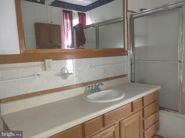 bathroom featuring vanity, combined bath / shower with glass door, and tasteful backsplash