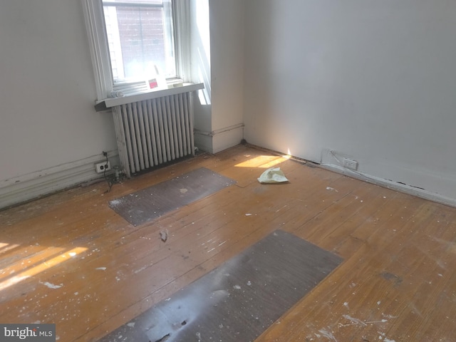 empty room with wood-type flooring and radiator heating unit