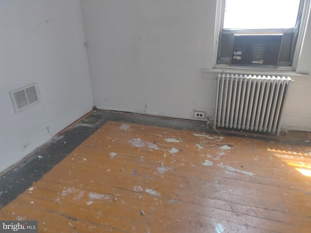 spare room featuring wood-type flooring and radiator